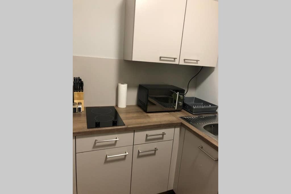 Una cocina equipada con microondas, tostadora y lavamanos.