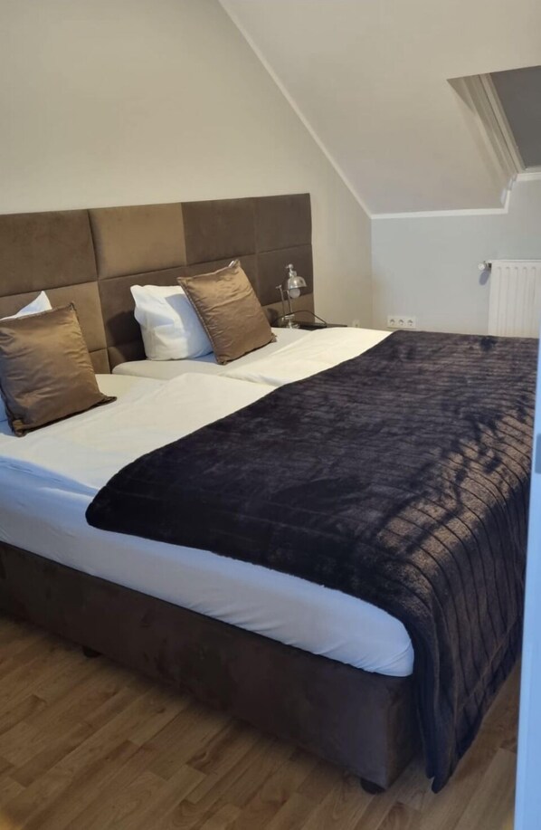 A bedroom with a sloped ceiling, a bed with a dark headboard, and a window. - Chillinghouse 9 (Siegburg)