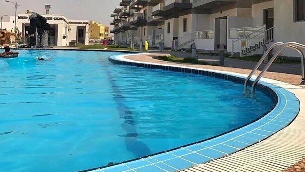 A modern residential building with a swimming pool. - Muhanna Chalets (Al Khiran)