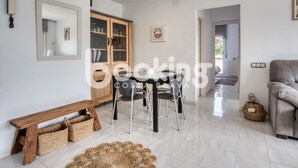 A modern living room with a wooden bench, a glass-top dining table, and a grey sofa.