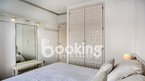 A bedroom with a large bed, a bedside table, a mirror, and two wardrobes.