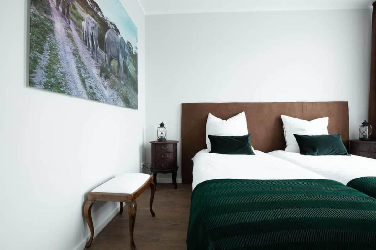 Une chambre à coucher avec un grand lit, deux tables de chevet, une petite table et un tableau au mur.