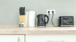 Uma bancada de cozinha com uma cafeteira, torradeira e um conjunto de facas.
