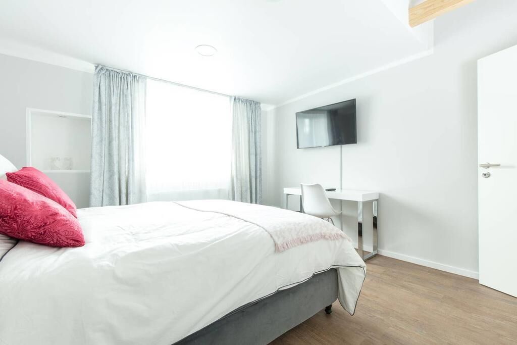 Un dormitorio moderno con cama, escritorio y televisor.