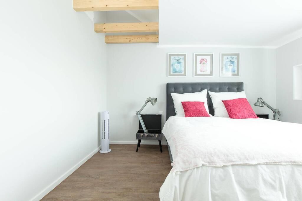 Un dormitorio con cama, mesitas de noche y un cuadro colgado en la pared.