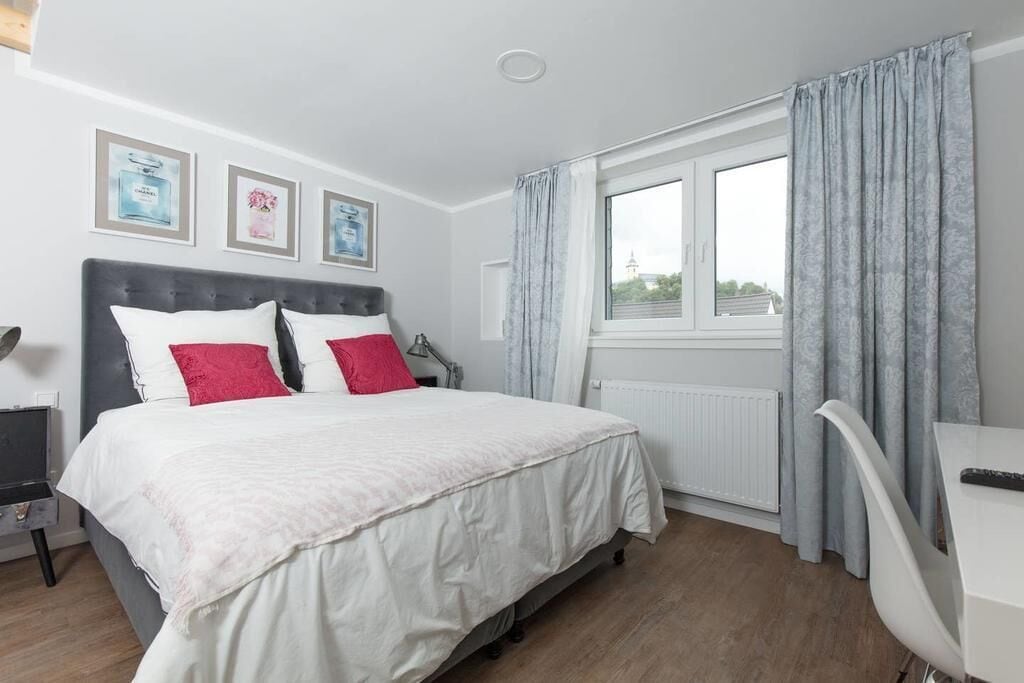 Ein Schlafzimmer mit einem Bett, einem Schreibtisch und einem Fenster mit Vorhängen.