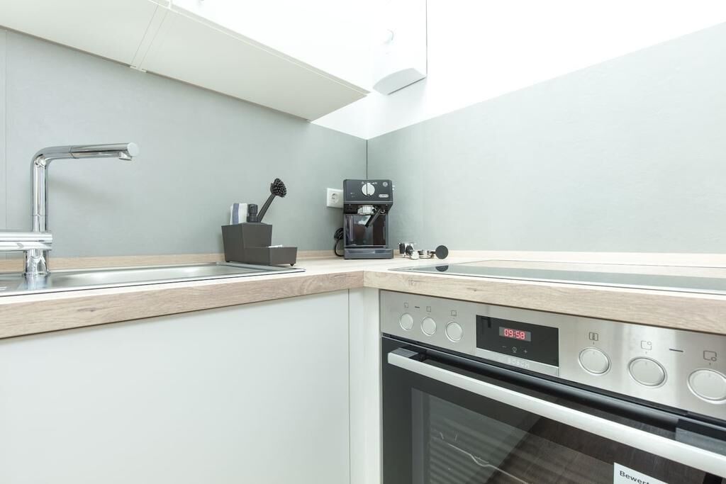 Una cocina moderna con horno empotrado, cafetera y lavamanos.