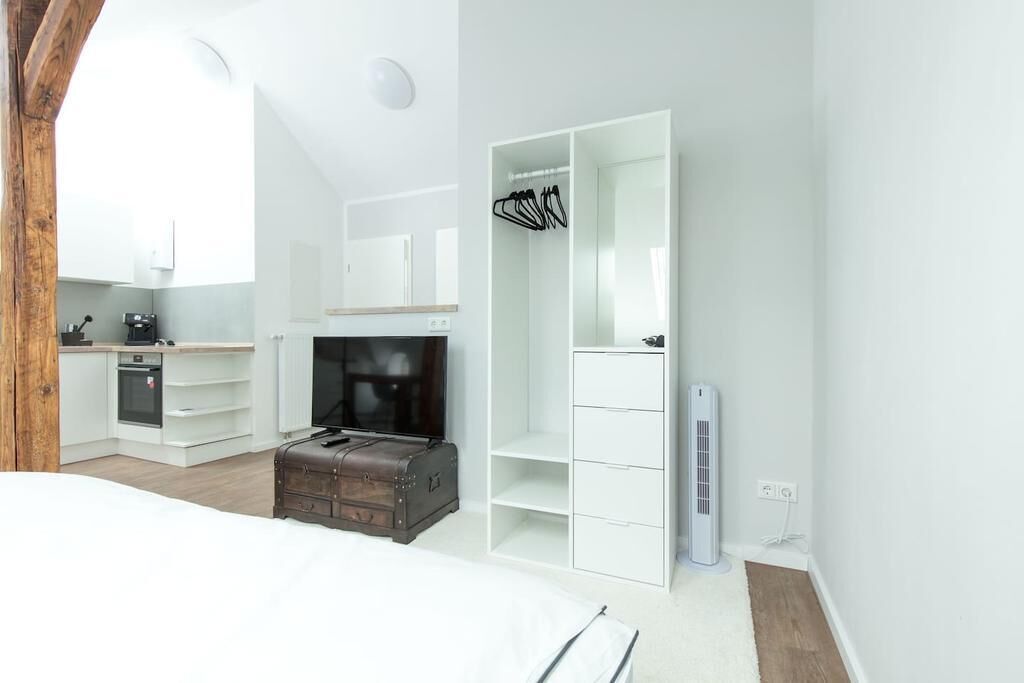 Un dormitorio moderno con una cama grande, un armario, una pequeña cocina y una chimenea.