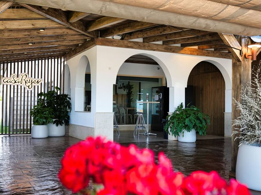 A covered outdoor area with wooden beams, white walls, and arches.