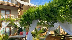 A rooftop terrace with a bed, a hammock, and a pergola covered in greenery. - Pousada Paraíso dos Ventos (Cruz)