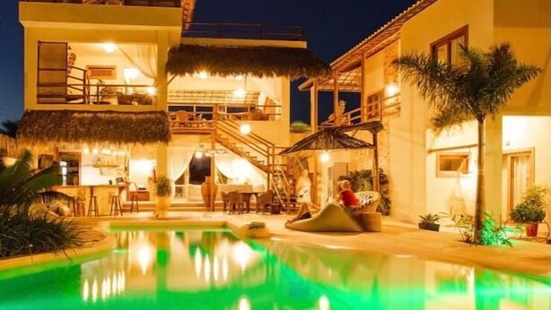 A two-story building with a swimming pool at dusk. - Pousada Paraíso dos Ventos (Cruz)