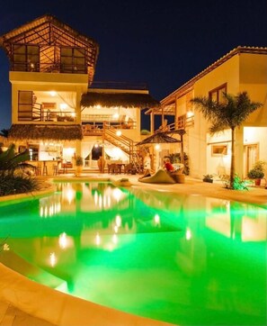Un edificio de dos pisos con piscina al anochecer.
