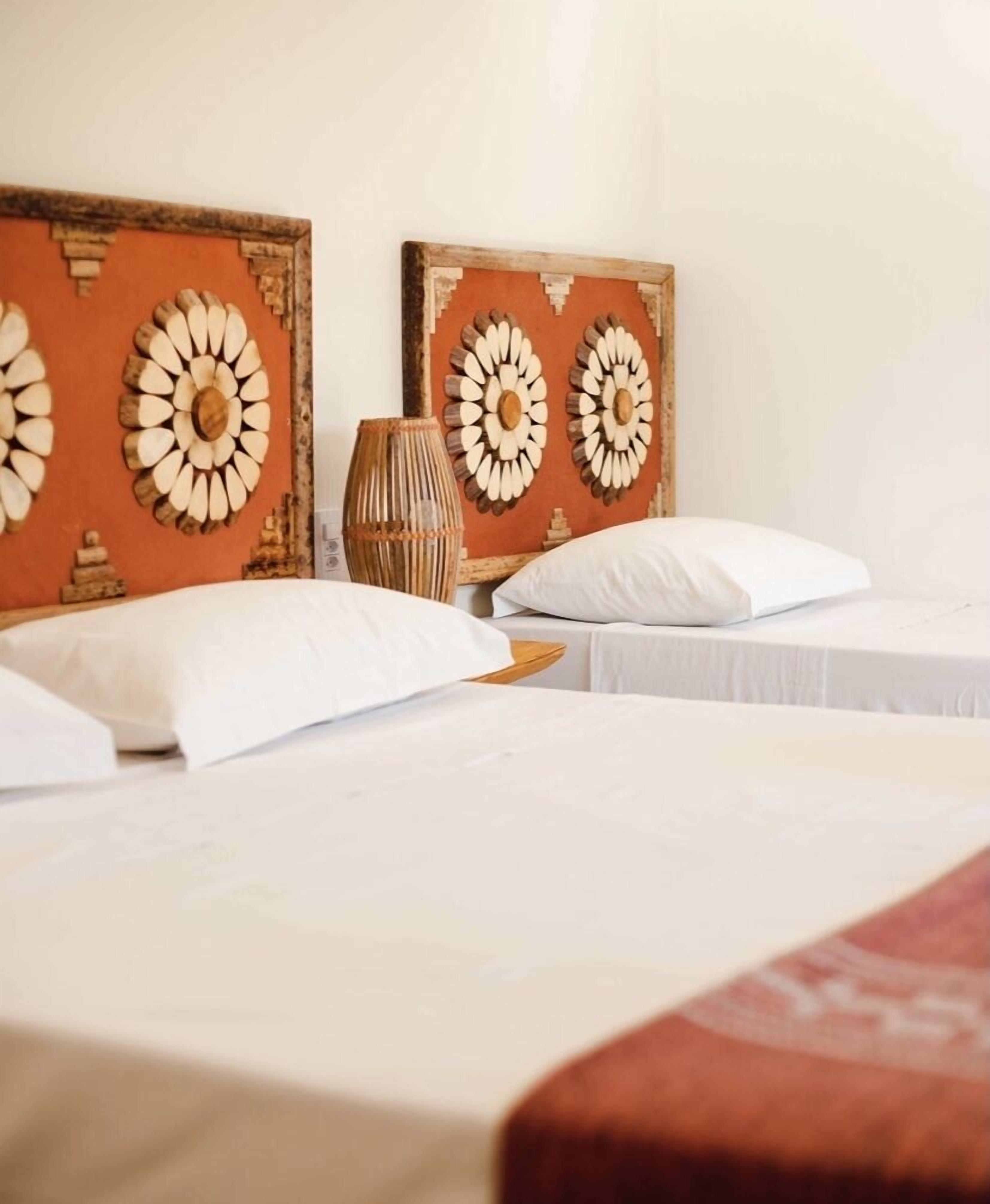 Habitación de hotel con dos camas, una mesita de noche y decoración en la pared.