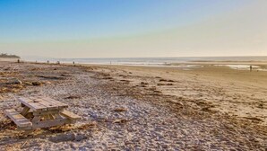 En strand med ett picknickbord i trä och en sandstrand.