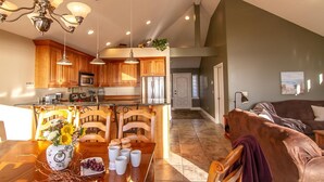 Una cocina amplia con armarios de madera, una isla central con sillas y una mesa de comedor dispuesta para una comida.