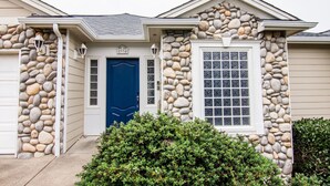 Una casa con fachada de piedra, una puerta azul y una ventana con diseño de cuadrícula.