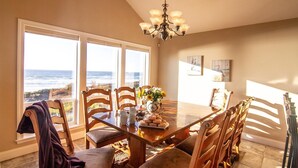 Comedor con vista al océano, un candelabro y sillas de madera.