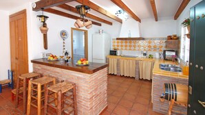 Eine Küche mit Kücheninsel aus Backstein, Holzstühlen, einem Kühlschrank und einer gefliesten Rückwand.