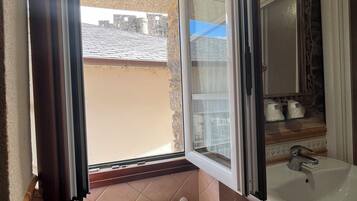 A bathroom with a window, a radiator, a sink, and a towel hanging on a rack.