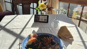 Una mesa de comedor con un plato de comida, una copa de vino y un cartel con el menú.