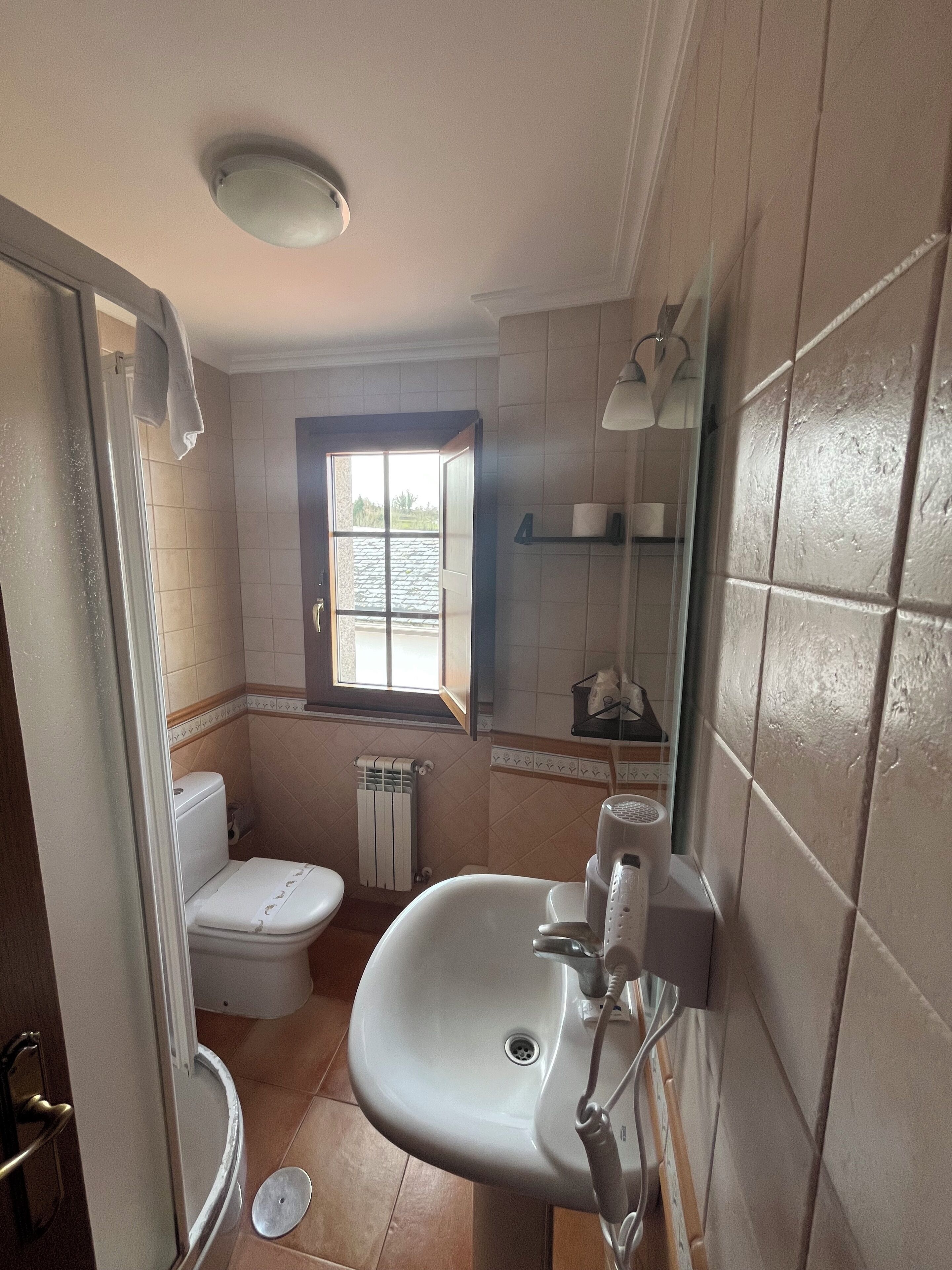 Une salle de bain avec des toilettes, un lavabo et une fenêtre.