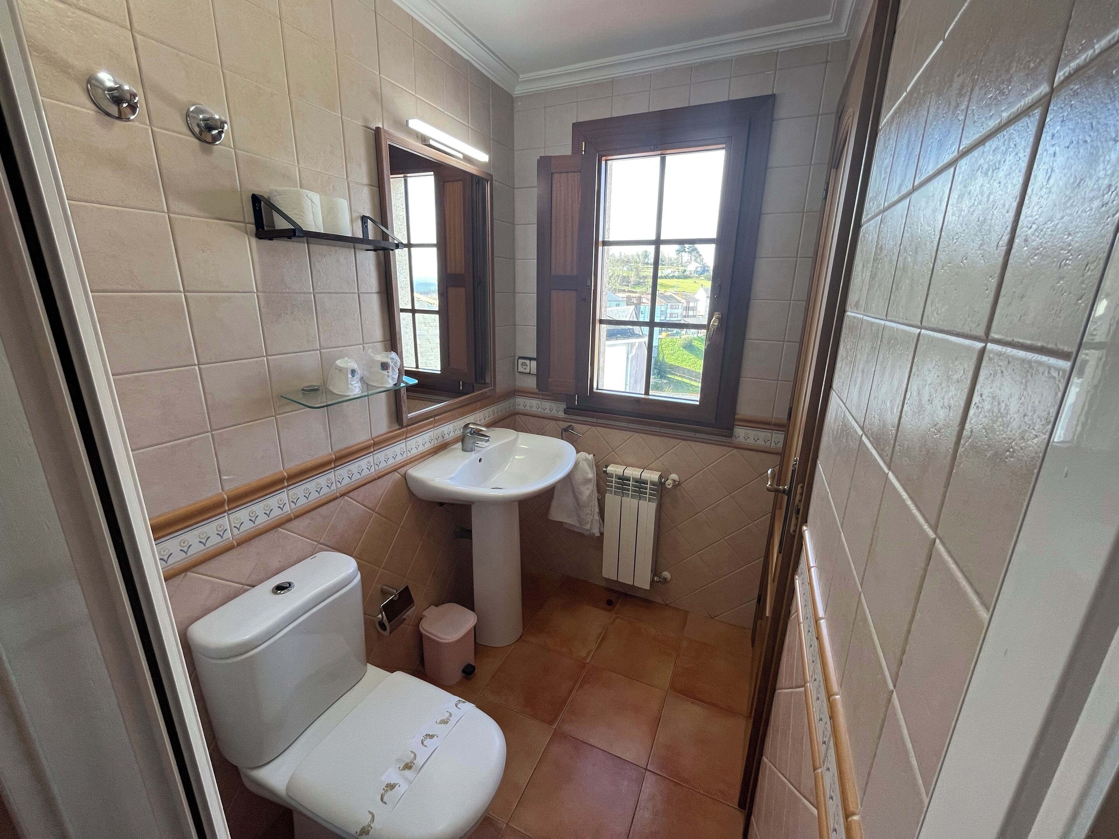 A bathroom with a toilet, sink, and window.