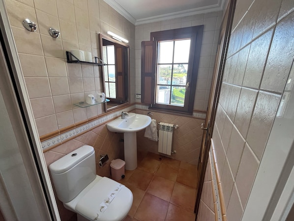 Un baño con inodoro, lavamanos y ventana.