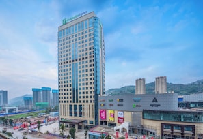 A high-rise hotel with a prominent sign, surrounded by other buildings and a busy street. - Holiday Inn Express Chongqing Zhongxian by IHG (Chongqing)