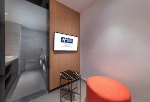 A hotel room with a washing machine, a wooden panel wall, a framed sign, and a small stool. - Holiday Inn Express Chongqing Zhongxian by IHG (Chongqing)