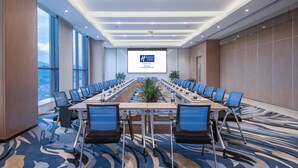 Una sala conferenze con un lungo tavolo, sedie, uno schermo per proiettore e vista sulla città.