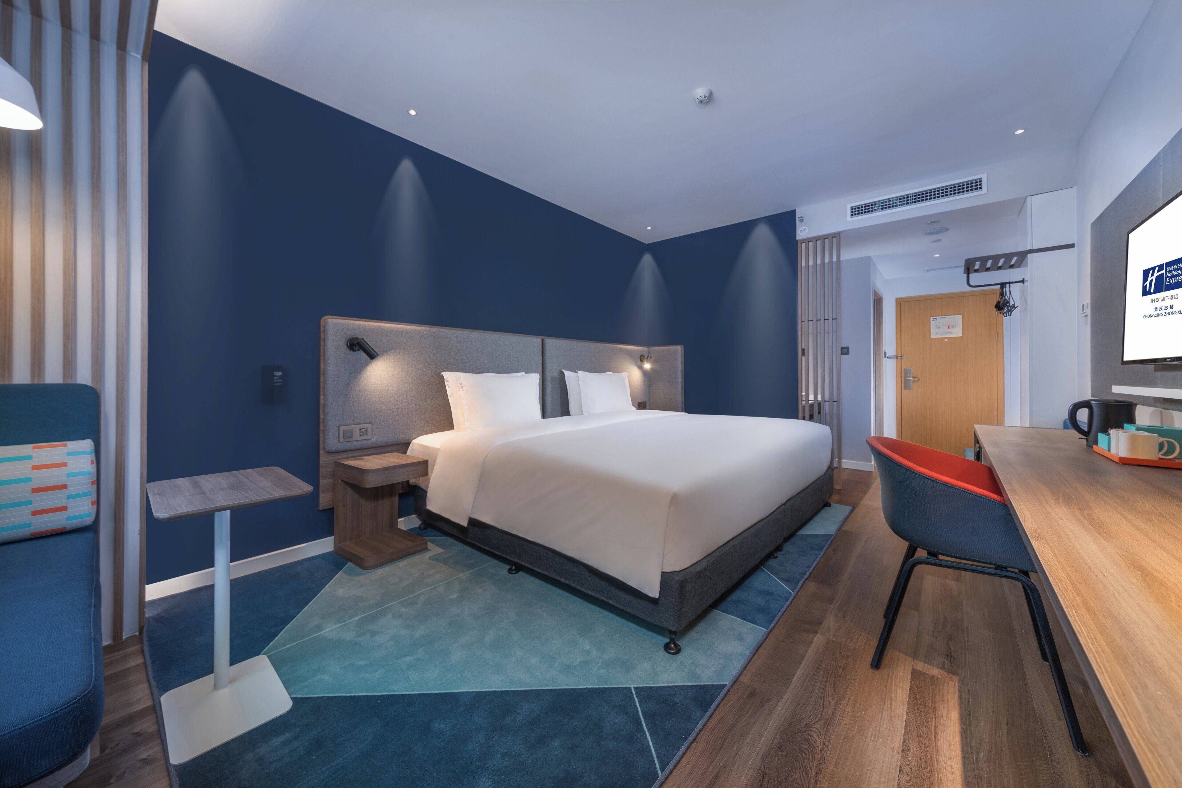 A modern hotel room with a large bed, a desk, and a chair.
