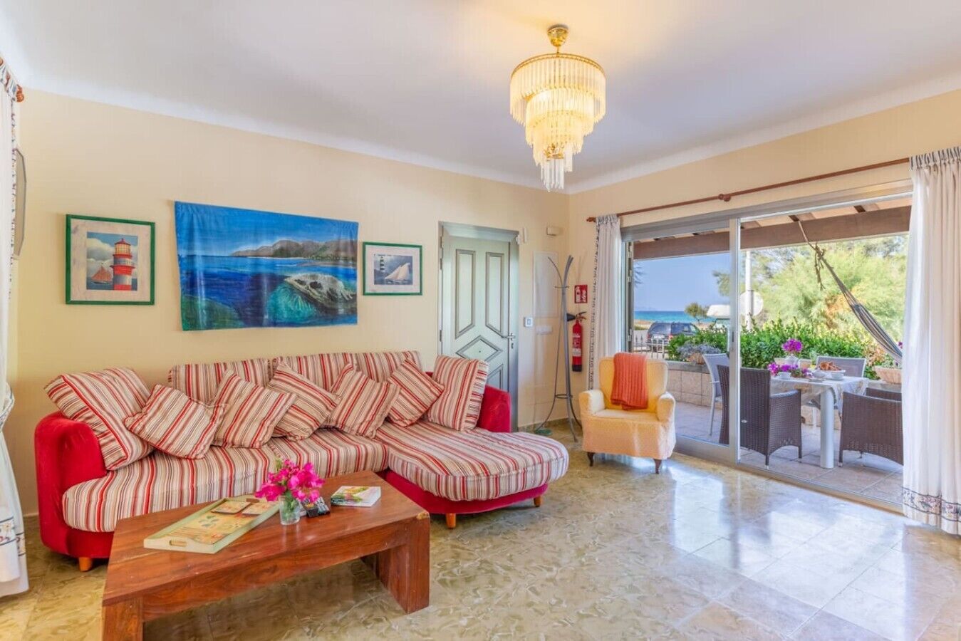 A living room with a sofa, a coffee table, and a painting of a lighthouse.
