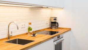 A modern kitchen with a wooden countertop, stainless steel sink, and a built-in oven. - BENSIMON apartments Charlottenburg (Berlin)