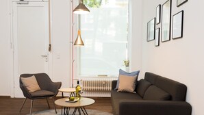 A modern living room with a sofa, armchair, coffee table, and pendant lights. - BENSIMON apartments Charlottenburg (Berlin)