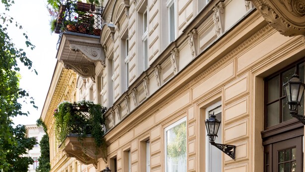 A historic building with ornate architecture, a cobblestone street, and hanging plants. - BENSIMON apartments Charlottenburg (Berlin)