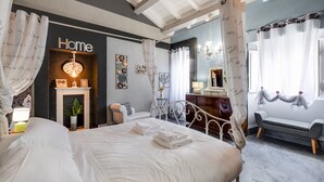 Une chambre à coucher avec un lit, une table de chevet avec une lampe, une cheminée, un miroir et une fenêtre avec des rideaux.