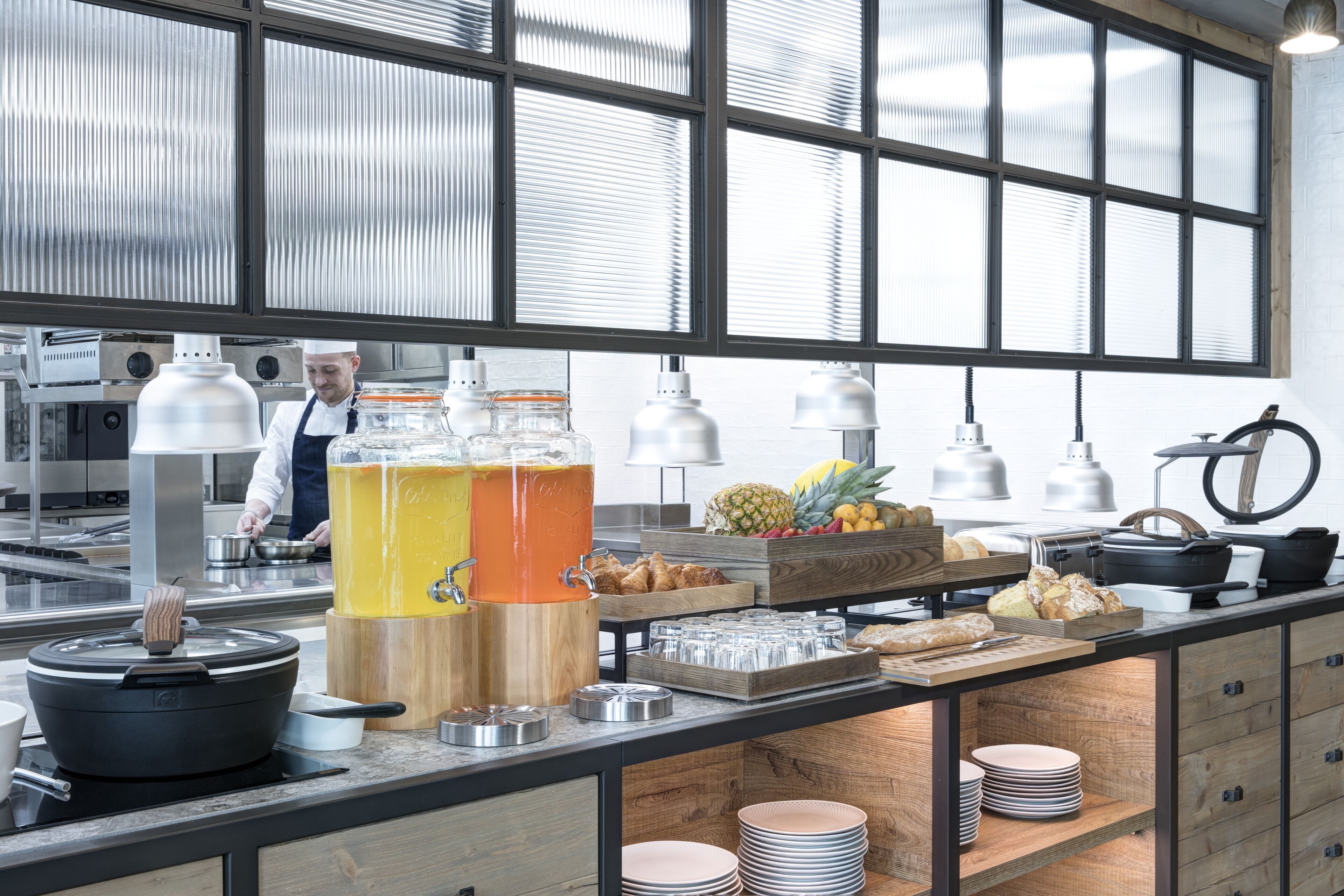 Ein Frühstücksbuffet mit Koch, Obstauslage und verschiedenen Speisen.