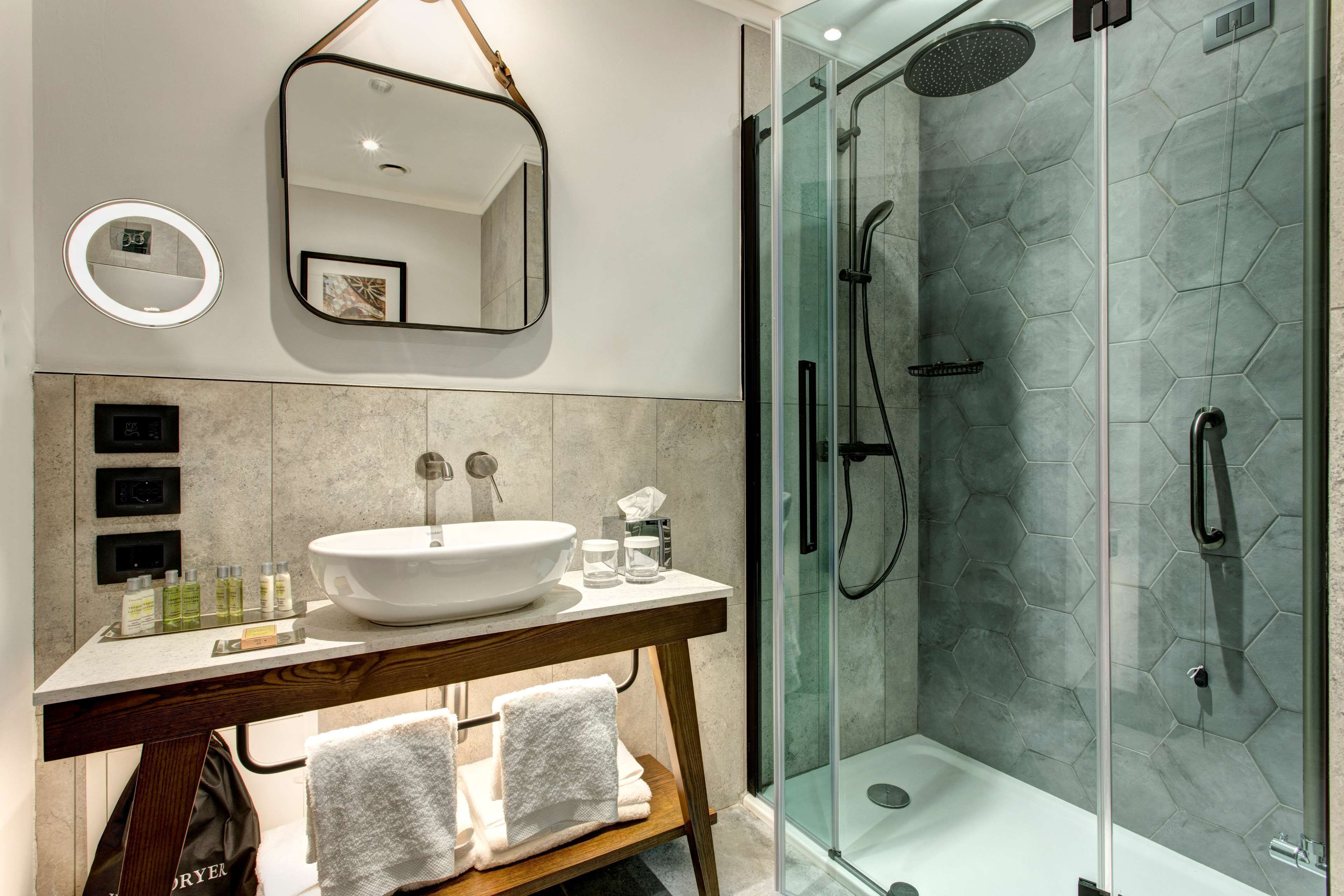 Une salle de bain moderne avec un grand lavabo, un miroir et une douche à parois de verre.