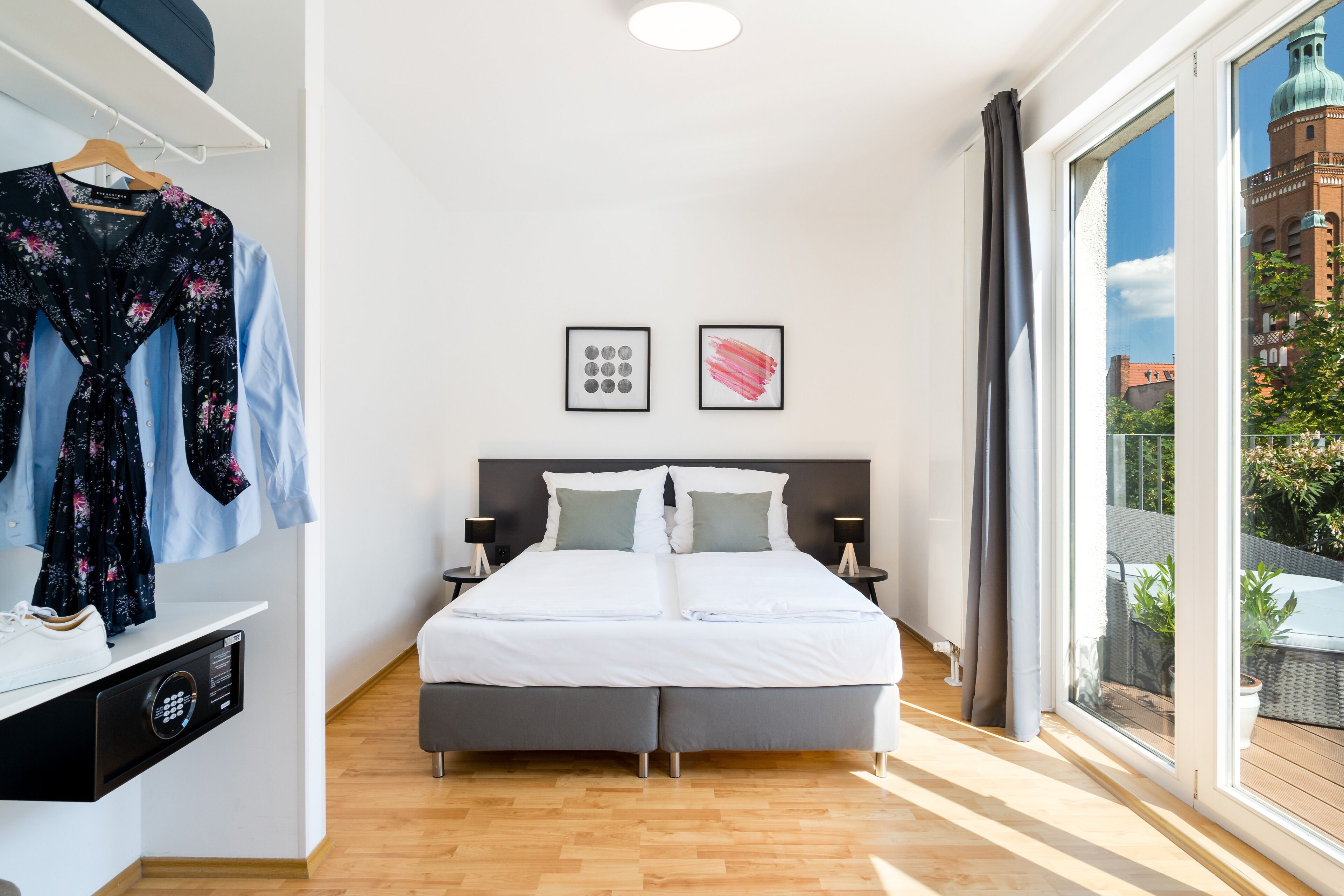 Ein modernes Schlafzimmer mit einem großen Bett, einem Kleiderschrank und Blick auf eine Stadtansicht.