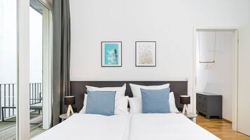 Une chambre d’hôtel avec un grand lit, deux tables de chevet, une commode, une armoire et un balcon avec une balustrade.