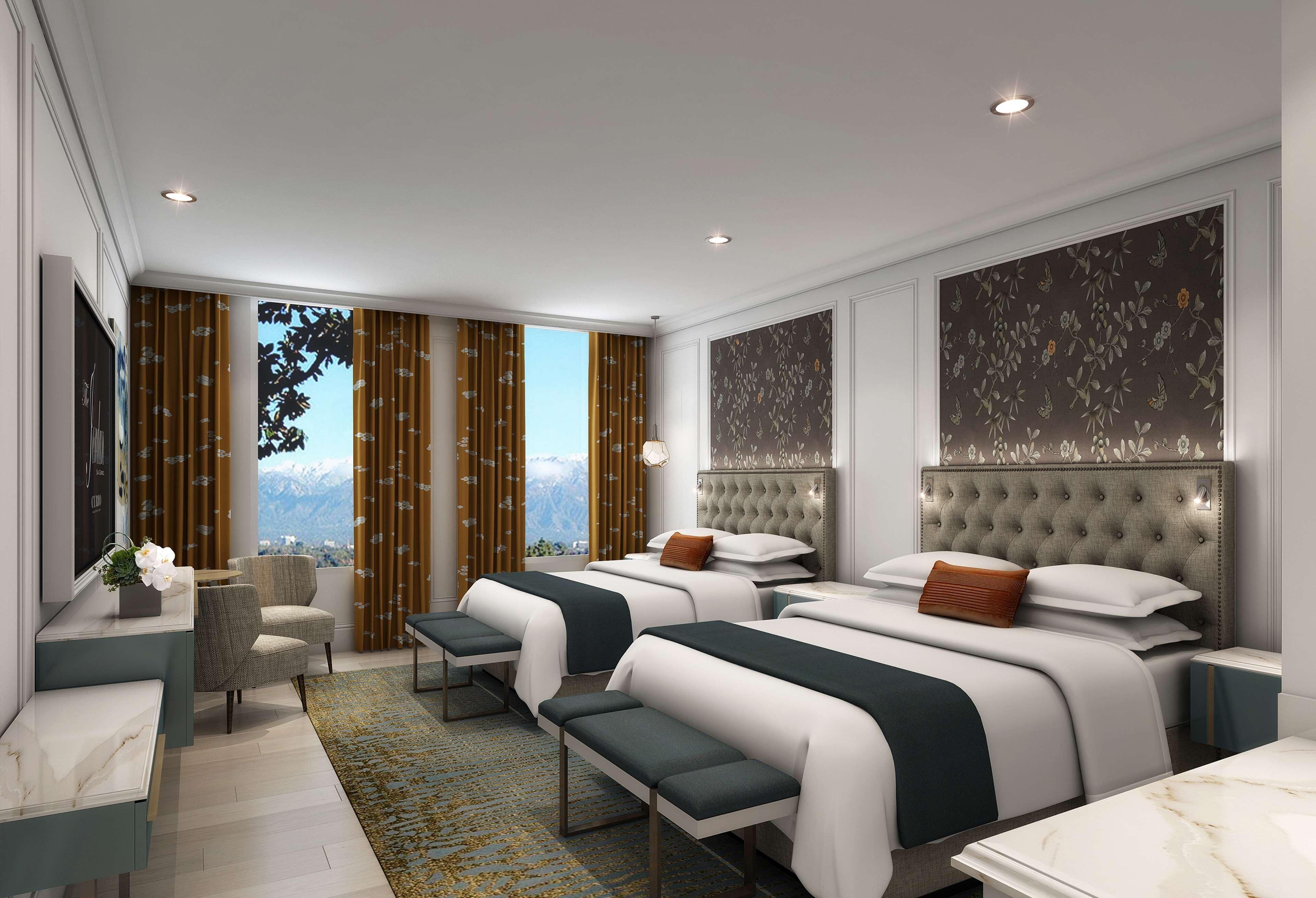 Una moderna camera d'hotel con due letti, una zona relax e vista sulle montagne.