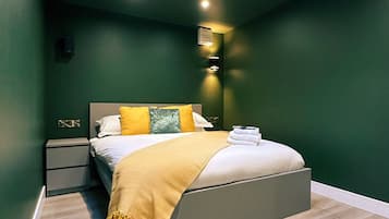 Ein modernes Schlafzimmer mit Bett, Nachttischen, einem Beistelltisch und einer Deckenleuchte.