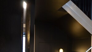 A staircase with black railings and white steps, leading to a landing with a light fixture. - Sky City Apartments (Coventry)