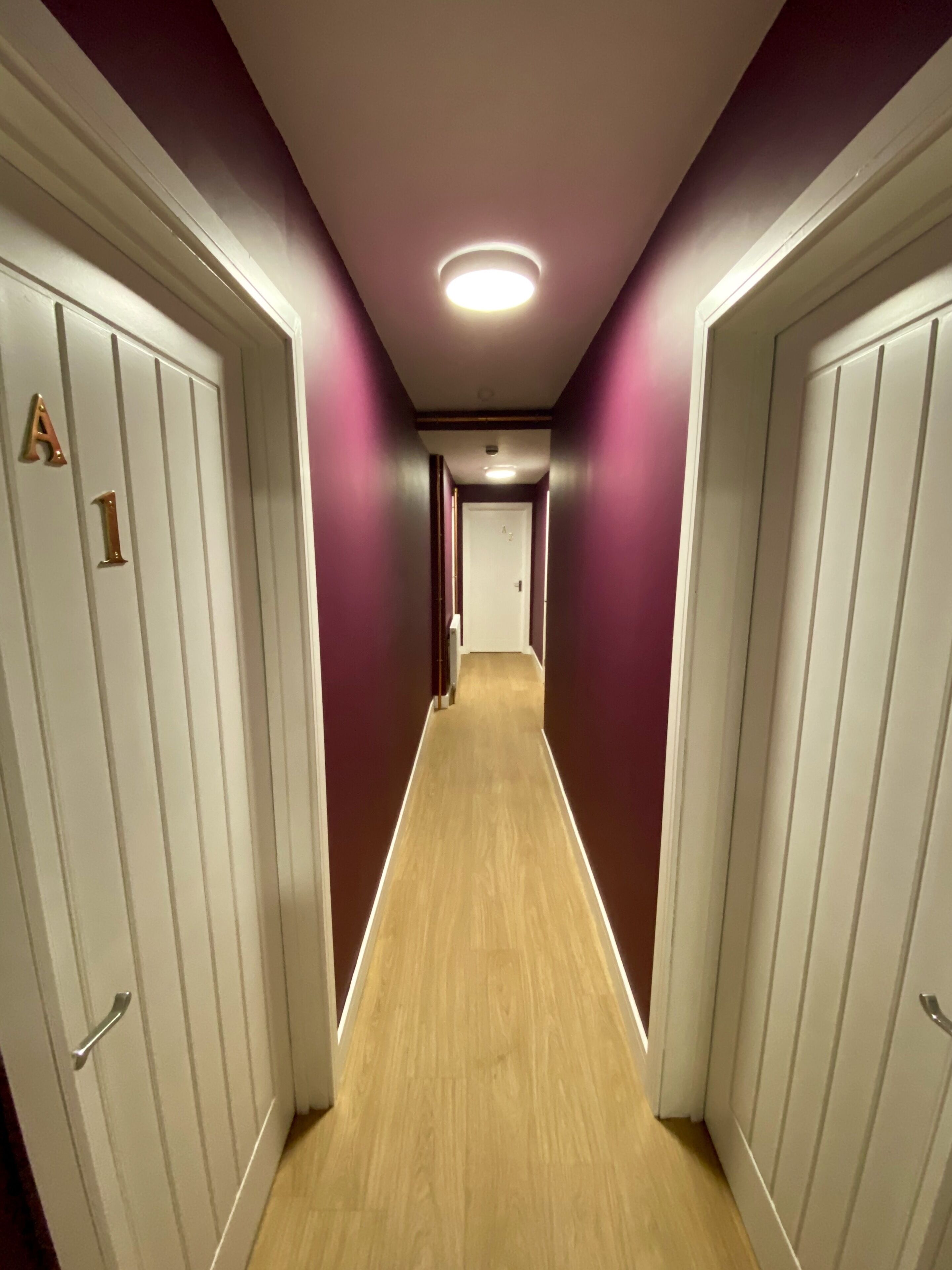 Un couloir avec des portes blanches, chacune portant un numéro.