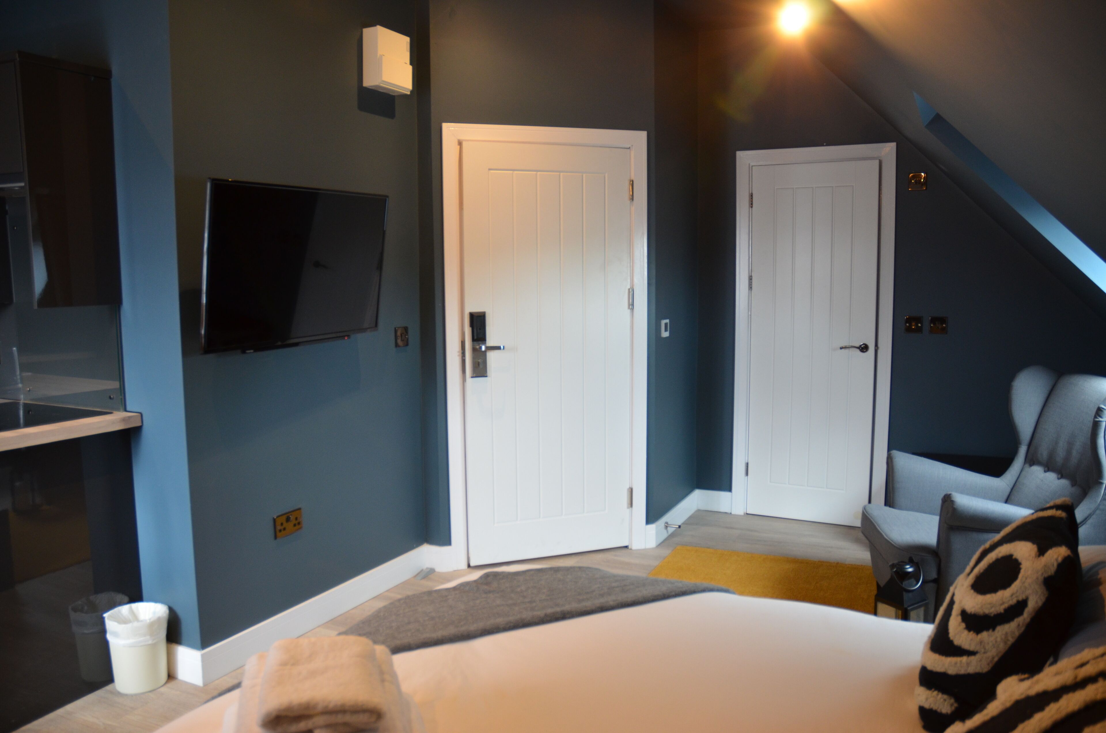 Un dormitorio con cama, televisor, sillón y puerta.