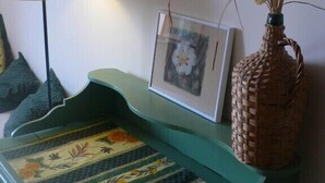 Una habitación con un sofá color turquesa, una lámpara, un cuadro enmarco y una cesta tejida con plantas secas.