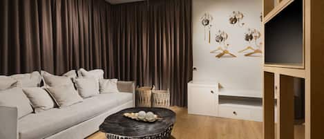 A modern living room with a sofa, a round coffee table with decorative items, a white cabinet, and a wooden TV stand.