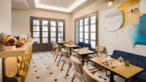 Un caffè moderno con tavoli in legno, sedute confortevoli e ampie vetrate che si affacciano sulla strada.