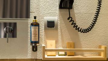 A bathroom with a hand soap dispenser, a soap dish, and a telephone mounted on the wall.