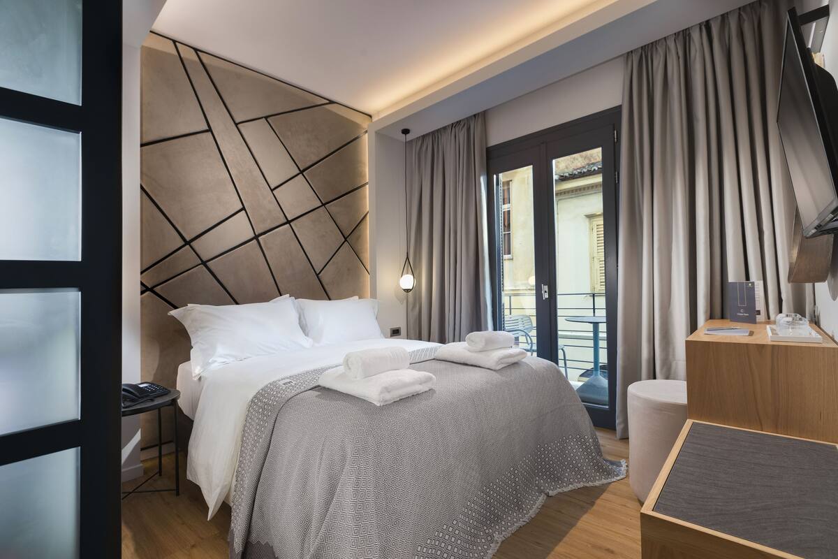 Una habitación de hotel moderna con una cama, una mesita de noche y un escritorio con una silla.
